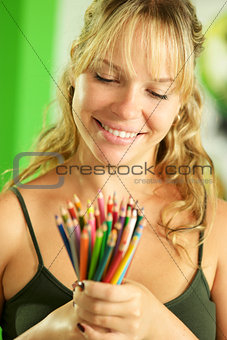 Young female artist looking at colored pencils and smiling
