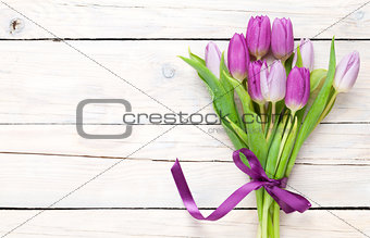 Purple tulip bouquet over wooden table