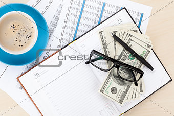 Office desk with reports, blank notepad and money cash
