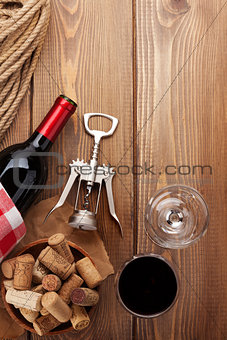 Glass of red wine, bottle and corkscrew on rustic wooden table