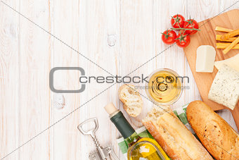 White wine, cheese and bread on white wooden table background