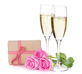 Two champagne glasses, gift box and pink rose flowers