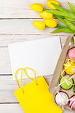 Easter background with colorful eggs, yellow tulips and greeting