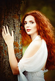Closeup portrait of a beautiful ginger woman near the tree