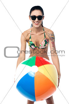 Bikini clad woman playing with beach ball