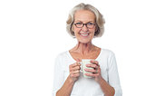Smiling bespectacled old lady drinking coffee