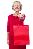 Cheerful old woman holding shopping bag