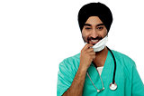 Smiling male doctor removing surgical mask