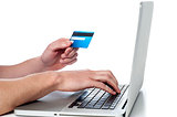 Mans hand holding debit card and using laptop