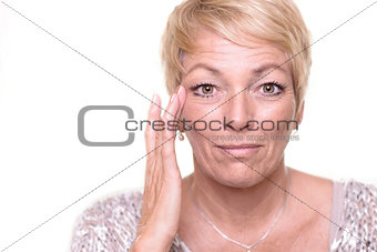 Attractive senior blond woman checking her complexion