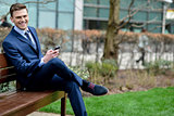 Businessman with his phone on the bench