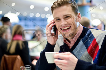 Young man using mobile phone in cafe