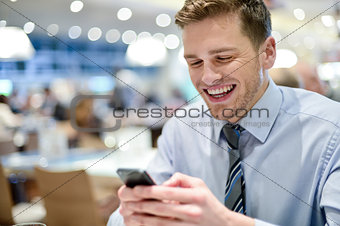 Happy young executive sitting with smartphone