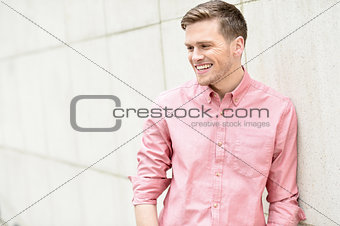 Happy young man standing against wall