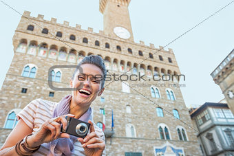 Portrait of happy young woman with photo camera in front of pala