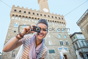 Happy young woman taking photo in front of palazzo vecchio in fl