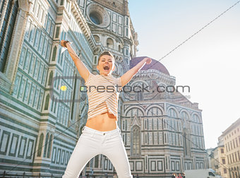 Happy young woman jumping in front of cattedrale di santa maria 