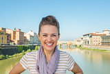Portrait of smiling young woman standing on bridge overlooking p