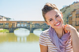 Portrait of happy young woman sitting on bridge overlooking pont