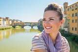 Happy young woman sitting on bridge overlooking ponte vecchio in