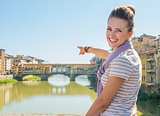 Happy young woman pointing on ponte vecchio in florence, italy