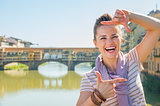 Portrait of happy young woman standing on bridge overlooking pon