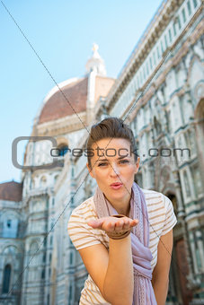 Portrait of happy young woman blowing kiss in front of cattedral