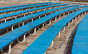 Row of blue wooden seats on a spectator grandstand photo. Bench in the park for the show