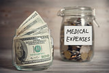 Dollars and coins in jar with medical expenses label
