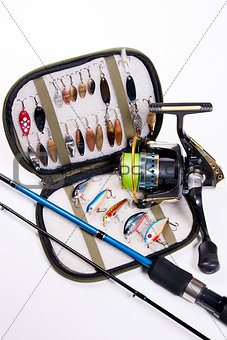 Fishing rod and lures with bag for baits on white.