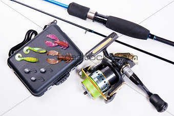 Fishing rod and reel with box for baits on white.