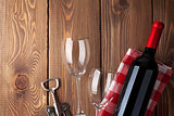 Red wine bottle, glasses and corkscrew on wooden table