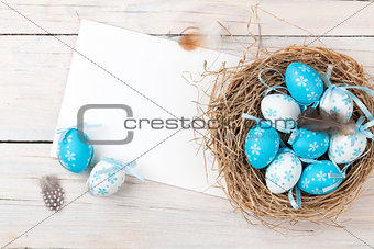 Easter background with blue and white eggs in nest and greeting 
