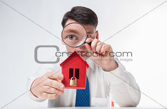 Man with a magnifying glass and paper house