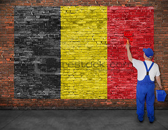 House painter paints flag of Belgium on brick wall