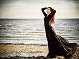 Beautiful goth girl standing on sea beach