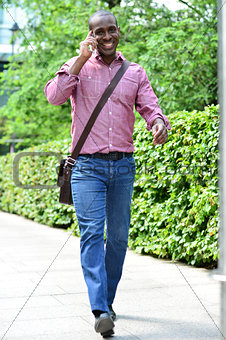Casual man talking on the phone while walking