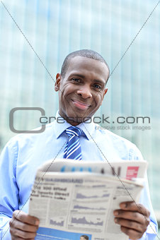 Handsome male executive reading a newspaper