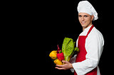 Handsome chef holding vegetables bowl