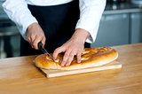 Male chef cutting bread loaf