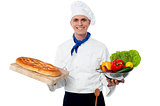 Smiling chef holding bread and vegatables