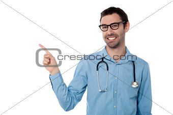 Smiling doctor pointing copy space area