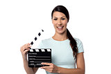 Smiling woman holding a movie slate in hand