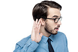 Corporate man listening with hand on ear
