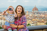 Happy mother and baby girl taking photo against panoramic view o