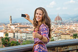 Happy young woman taking photo of panoramic view of florence, it