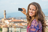 Smiling young woman taking photo of panoramic view of florence, 