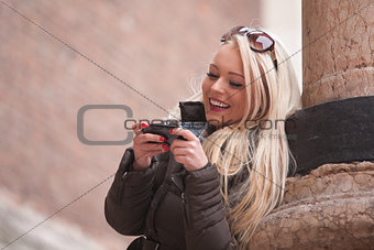 blonde girl outdoors with her mobile phone