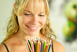 Young female artist holding colored pencils and smiling