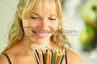 Young female artist holding colored pencils and smiling